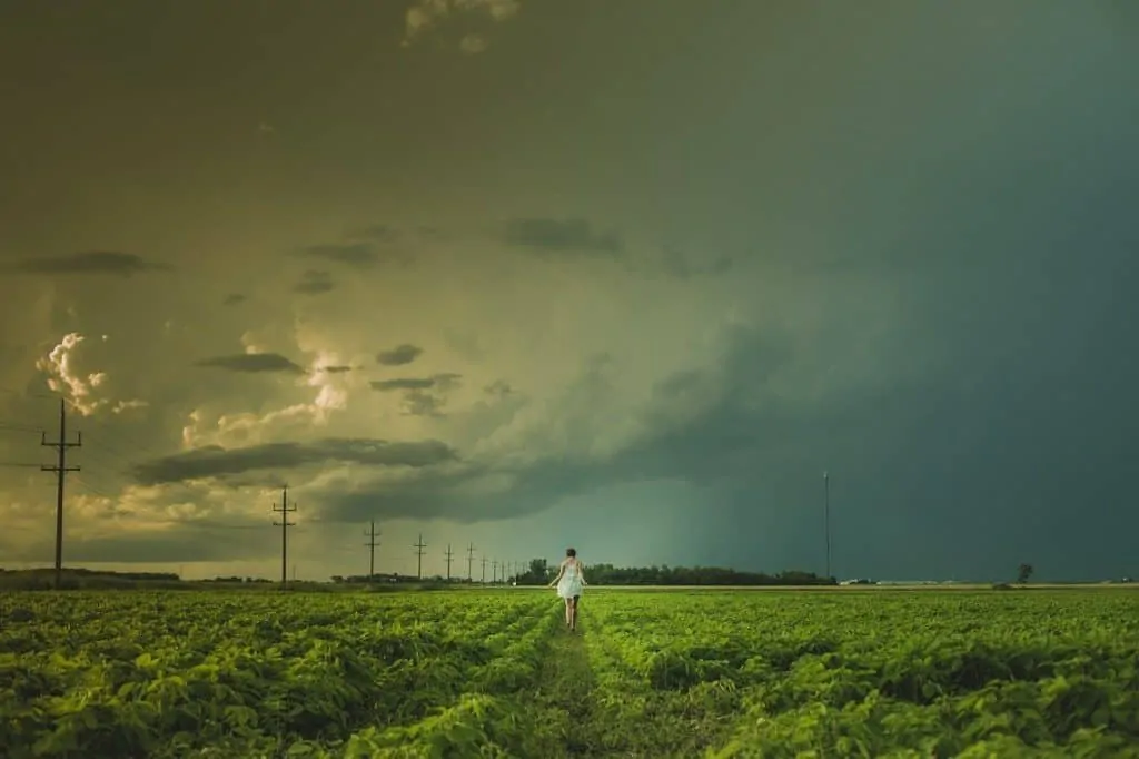photo of woman in walking barefoot in a field with a blue sky