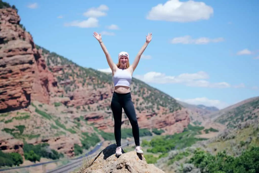 photo of woman holding her arms in the air in jubilation on the top of a hill: HSCT-things to consider