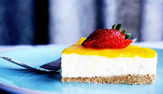 photo of a piece of lemon cheesecake with a strawberry on top
