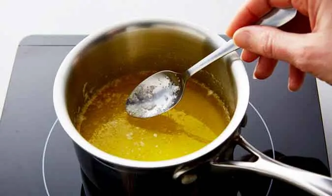 photo of a person stirring clarified butter in a saucepan