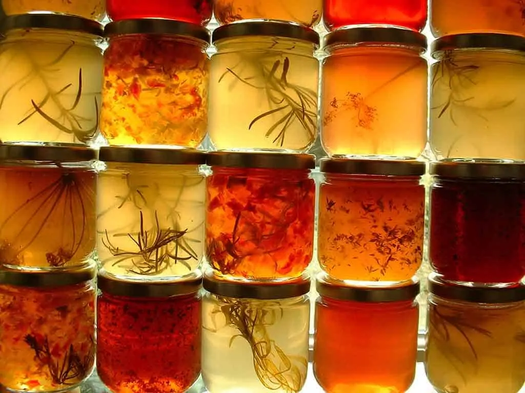 Photo of jars of oil with herbs in them which reflect the topic of the page - best fats to eat on a keto diet.