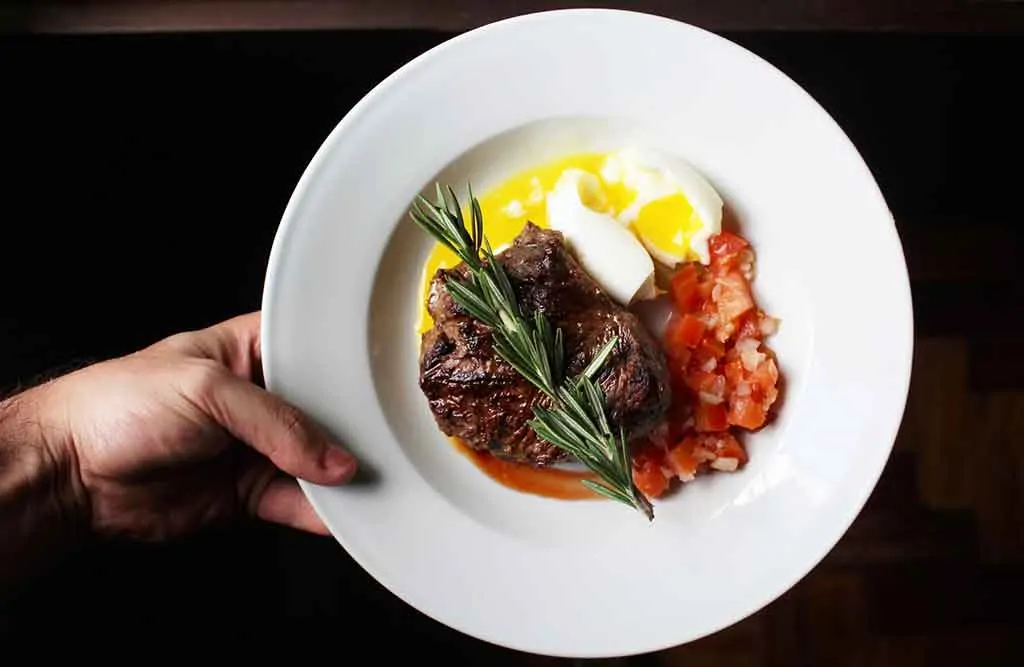 photo of a white plate with steak, eggs and tomatoes, a keto friendly meal; Ketogenic Diet