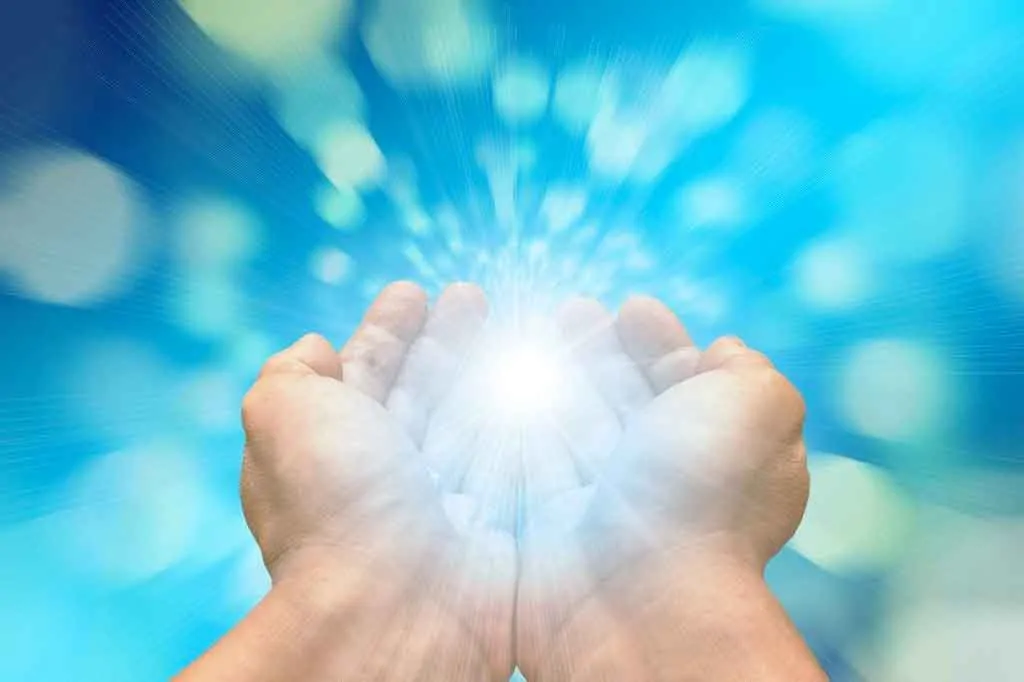 photo of two hands cupped together with light coming from the center, representing healing.