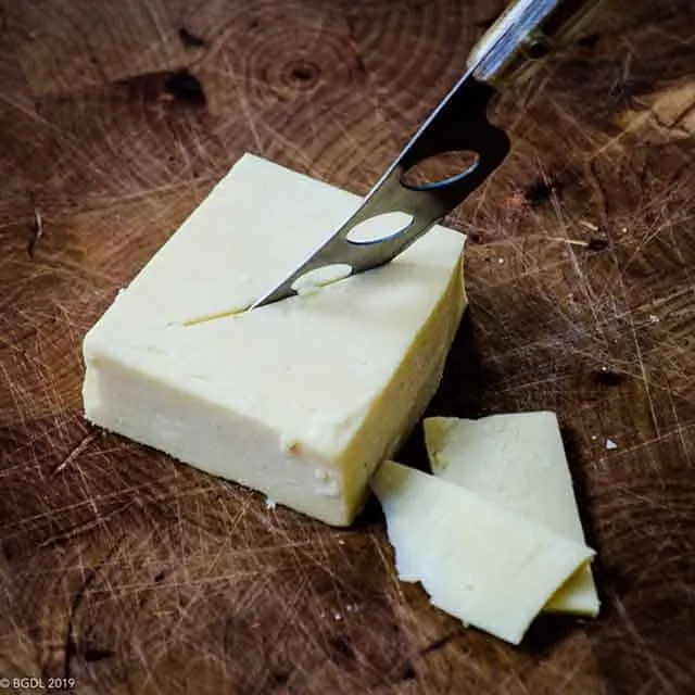 photo of cheddar cheese on a cutting board which reflects the topic of the page - Best dairy foods to eat on a keto diet.