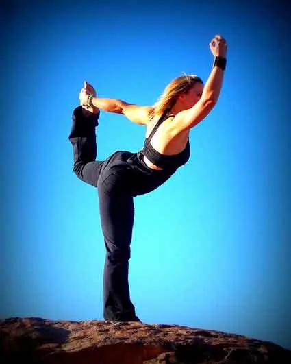 photo of a woman doing yoga on .top of a mountain